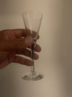 Elegant smal snapsglas i glas - Säljer ett elegant och smalt snapsglas i genomskinligt glas. Glaset har en hög fot och konisk form, perfekt för snaps eller likör. Enkel och stilren design som passar till många tillfällen.
