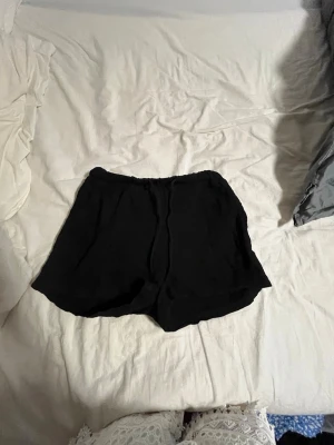 Svarta loose shorts med resårmidja - Säljer ett par svarta shorts med loose fit och resår i midjan. De är enkla och stilrena, perfekta för varma dagar. Materialet känns lätt och luftigt, vilket gör dem sköna att bära hela sommaren.