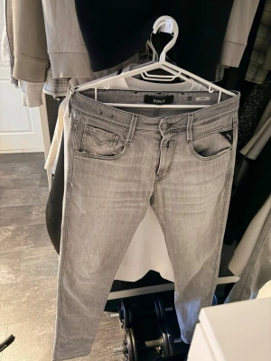 Replay ljusgrå slim fit jeans - Snygga ljusgrå slim fit jeans från Replay med klassisk femficksmodell och svarta detaljer på fickan. Jeansen har en modern tvätt och raka ben, perfekta till en avslappnad streetwear-look. Materialet är mjukt och stretchigt för extra komfort.