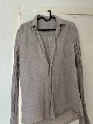 Beige linneskjorta från Stenströms - Säljer en beige långärmad skjorta från Stenströms i svalt och luftigt linne. Skjortan har klassisk krage, knappar framtill och en avslappnad passform. Perfekt för varma dagar och enkel att styla till olika outfits.