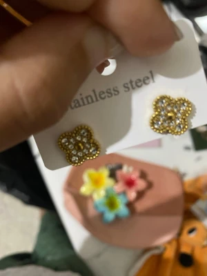 Guldiga blomformade örhängen rostfritt stål guldpläterad - Snygga örhängen i rostfritt stål med guldfärgad finish. De har en söt blomform och är dekorerade med små glittrande stenar som ger extra bling. Perfekta för att lyfta vilken outfit som helst!