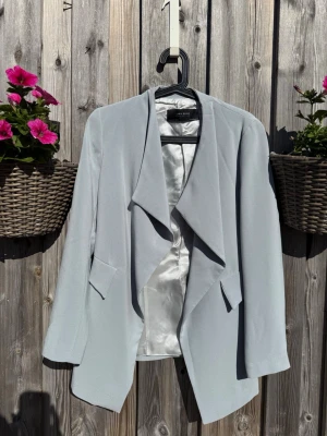Ljusblå kavaj från Zara Basic (XS) - Snygg ljusblå kavaj från Zara Basic Collection med avslappnad passform och öppen front. Kavajen har breda slag, två dekorativa fickor och är helfodrad med silkeslen insida. Perfekt för att lyfta vilken outfit som helst.