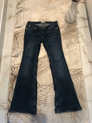 Mörkblå bootcut jeans från Lager 157 - Säljer ett par mörkblå bootcut jeans från Lager 157 med klassisk femficksdesign och utsvängda ben. Jeansen har normal midja och är tillverkade i ett mjukt denimtyg. Perfekta för dig som gillar retrostil och vill ha ett par riktigt snygga jeans. Är öppen med prisförslag😊