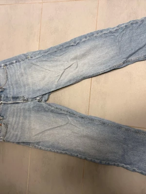 Ljusblå relaxed jack & Jones jeans - Säljer ett par ljusblå jeans med relaxed passform. Jeansen har en avslappnad vintage-look med slitningar och är tillverkade i denim. Perfekta för en casual och trendig stil. Lite slitage längst ned på byxbenet