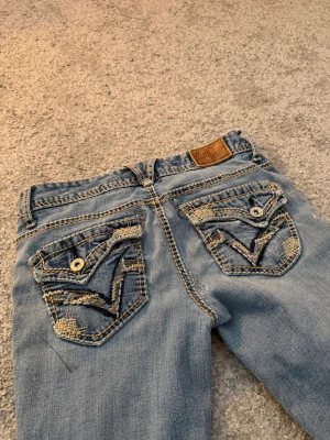 Ljusblå bootcut jeans med slitningar - Säljer ett par ljusblå bootcut jeans från Vanity med slitna detaljer på både fram- och baksida. Jeansen har en del slitningar och fläckar, slitningarna är inte hål!! Köpta på vinted för nåt pris men kommer inte till användning!