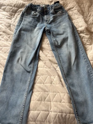 Ljusblå raka jeans Levis  - Säljer ett par ljusblå jeans med rak passform och hög midja. Klassisk femficksmodell med knappgylf och bälteshällor. Jeansen har en avslappnad vintage-look och är tillverkade i denim. Perfekta för en chill och trendig stil.