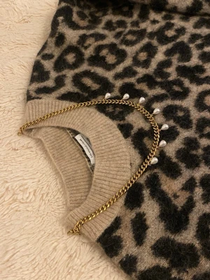 Guldfärgat halsband med pärlor - Snyggt halsband i guldfärgad rostfritt med sju hängande vita pärlor. Kedjan har en chunky design som ger ett trendigt intryck och pärlorna ger en elegant touch. Perfekt accessoar för att lyfta din outfit.