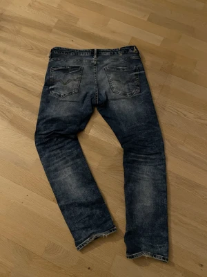Mörkblå slim fit jeans med slitningar - Säljer ett par mörkblå slim fit / staright jeans med snygga slitningar och tvättade detaljer. Klassisk femficksmodell med dragkedja och knapp i midjan. Jeansen har en modern passform och är perfekta för en avslappnad streetstil. Det defekter som finns visas, men personligen tycker jag de bidrar till en snyggare look. Från guess. Nytt pris 1600❌ mitt pris 150✅