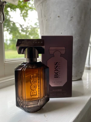 BOSS The Scent Absolute EdP 50ml - BOSS The Scent Absolute från Hugo Boss är en elegant parfym i en lyxig, mörkbrun glasflaska med metallock. Doften är en Eau de Parfum och flaskan rymmer 50 ml. Förpackningen är stilren i mörklila och bronsfärgade toner.