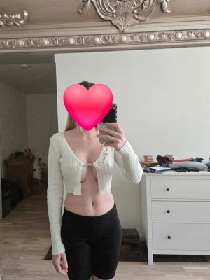 Vit croppad ribbad bolerotopp - Trendig vit croppad bolerotopp från H&Mi ribbad bomullsmix. Toppen har lång ärm, djup v-ringning och snygg knäppning framtill med metallring. Perfekt för att lyfta din outfit med en edgy touch. 