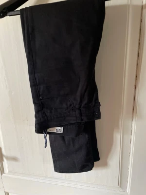 Svarta jeans från Crocker - Säljer ett par svarta jeans från Crocker, modell CR-3322. Klassisk rak passform med fem fickor och bälteshällor. Jeansen är tillverkade i bomull med lite stretch för extra komfort. Perfekta till en avslappnad och stilren look.