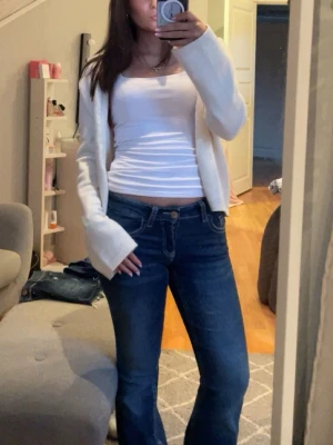 Blå bootcut jeans med broderade fickor - Säljer ett par blå bootcut jeans med snygga broderade bakfickor och vita knappar. Jeansen har låg midja och är köpta på Gina tricot, använda fåtal gånger. Köpta för 400 