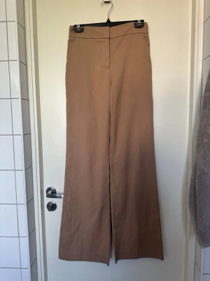 Beiga vida byxor från H&M 34 - Snygga beiga byxor från H&M med hög midja och vida ben. Byxorna har dragkedja i sidan och är tillverkade i ett mjukt bomullsmaterial. Perfekta för en trendig och avslappnad look.