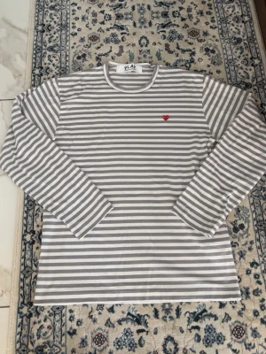 Comme des Garcons Longsleeve striped - Grå longsleeve från CDG, helt ny i storlek L, skulle säga att efter ja tvättat den så sitter den mycket bättre, kan skicka mått om det behövs. Aldrig använd, äkta. Tvättalapp är avklippt