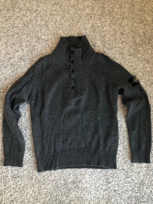 Grå stickad tröja från Stone Island - Vintage Stone Island stickad quarterzip. 80% ull och 20% nylon. Från säsongen A/W 2009, innan CLG-koder var en grej. Alltså ett riktigt häftigt vintage plagg. Passar något litet, S/M.