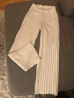 Beige ribbade mjukisbyxor - Säljer ett par beige mjukisbyxor från Zara med breda ribbade ränder och resår i midjan. Byxorna har raka ben och är gjorda i ett mjukt, stretchigt material.