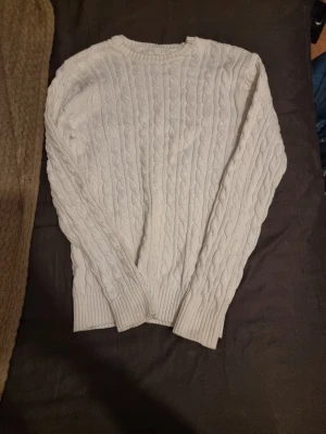 Vit kabelstickad tröja - Vit kabelstickad tröja från Lager 157 med rund halsringning och ribbade muddar. Tröjan har ett klassiskt flätmönster och är perfekt för lager-på-lager-stil. Passar dig som gillar enkel och stilren design. Från herr avdelningen