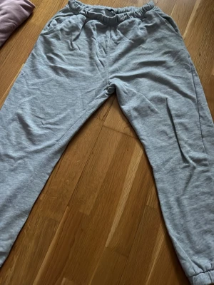 Grå mjukisbyxor från 157 - Säljer ett par klassiska grå mjukisbyxor från 157 med resår i midjan och muddar vid bensluten. Byxorna har en avslappnad passform och är tillverkade i mjukt bomullsmaterial. Perfekta för chill dagar eller när du vill vara extra bekväm.