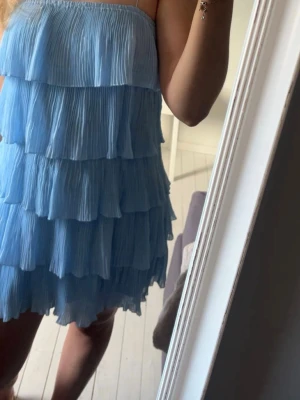 Ljusblå volangklänning - Söt ljusblå kortklänning med flera lager volanger. Den har tunna tunna axelband. Endast använd en gång!