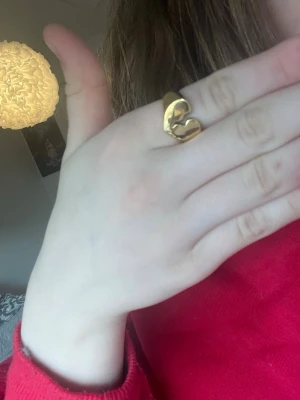 Guldfärgad ring med hjärtdesign  är ifrån en small bussniess  - Säljer en snygg guldfärgad ring med ett öppet hjärta som motiv. Ringen har en chunky känsla och är tillverkad i metall med blank finish. Perfekt för dig som gillar statement-smycken och vill addera lite edge till din stil.
