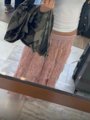 Rosa långkjol med spetsdetaljer - Säljer en romantisk rosa långkjol med vackra spetsdetaljer och resår i midjan. Kjolen har en luftig och flowy känsla, perfekt för varmare dagar. Passar dig som gillar en feminin och bohemisk stil.