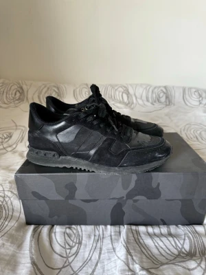 Svarta Valentino Rockrunner sneakers - Säljer ett par svarta Valentino Rockrunner storlek 41 men passar 40-42, box medföljer, de har ett litet hål i hälen
