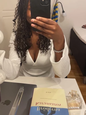 Vit omlottopp med v-ringning Gina Tricot -  vit omlottopp från Gina Tricot med djup v-ringning och långa ärmar. Toppen har en lätt ribbad struktur och knytband i midjan för en snygg passform. 