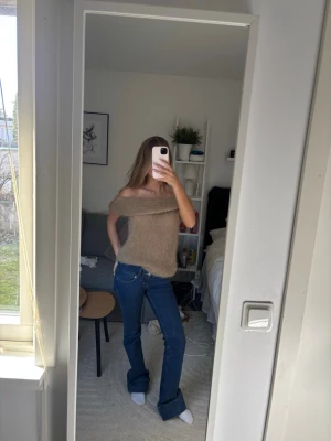 Brun off shoulder tröja - Säljer en supermjuk och fluffig beige off shoulder tröja. Tröjan har en bred krage som kan bäras nedanför axlarna för en avslappnad och trendig look. Perfekt att styla med jeans eller kjol för en cool vibe.