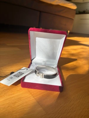 Hermés Clic H Armband - Hermés Clic H-armband i svart och silver, Armbandet är i bra skit! Finns tyvärr inte box eller kvitto men armbandet har gått igenom autentisering och godkännts som äkta, jag kan även skicka beviset!