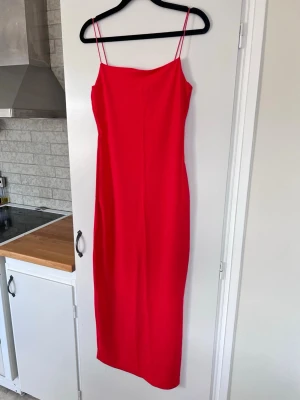 Zara röd stilren minimalistisk långklänning, stl M - Säljer en stilren röd minimalistisk midiklänning med tunna axelband och tight passform. Passar bra till mig som är en S/M. Går en liten bit över knäna. Mycket populär färg och perfekt till våren och sommaren! Använd en gång, som ny.