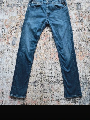  Replay grover jeans - Snygga blå jeans från Replay och klassisk femficksdesign. Jeansen har en mörk tvätt, detaljerade sömmar på bakfickan och Replay-logga på läderpatchen i midjan. Perfekta för dig som gillar stilrena och tidlösa jeans.