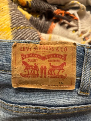 Ljusblå Levi's jeans  - Ljusblå jeans från Levi's med klassisk brun patch och röd Levi's-tag på bakfickan. Jeansen har fem fickor, raka ben och är tillverkade i slitstark denim. Perfekta för en avslappnad och tidlös stil.