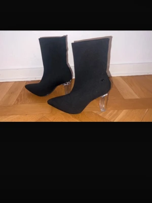 Svarta stövletter med transparent klack - Snygga svarta stövletter från NA-KD med spetsig tå och ribbad stickad textil. Skorna har en cool transparent klack som ger en modern look. Perfekt för dig som vill sticka ut och ha något trendigt på fötterna.
