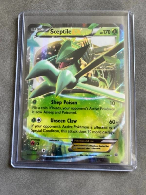 Pokémonkort Sceptile EX - Säljer ett Sceptile EX Pokémonkort med 170 HP. Kortet har en grön och gul holografisk design och visar Sceptile i en cool pose. Engelskspråkig text med attackerna Sleep Poison och Unseen Claw. Kortet ligger i ett genomskinligt plastskydd. Perfekt för samlare eller Pokémonfans.