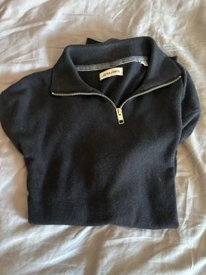 Svart halvzip-tröja Jack & Jones - Snygg svart långärmad tröja från Jack & Jones med halvzip och hög krage. Det är en stickad tröja i storlek M. Materialet känns mjukt och bekvämt, passar till många olika outfits. Priset går alltid att diskutera!