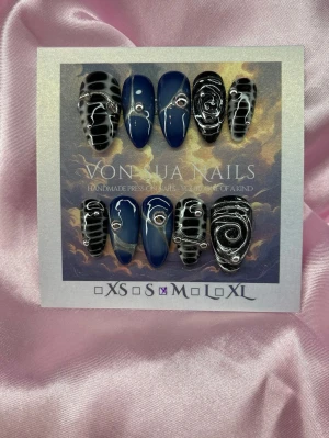 Midnight (M);Medium Almond - Unika handgjorda press-on naglar i en medium lång mandelform. Mix av djupblå och svarta naglar med vita swirl-mönster och silverfärgade dekorationer. Handgjorda och riktigt statement! Perfekt för dig som vill ha något extra.M: 16 mm, 12 mm, 12,5 mm, 11,5 mm, 10 mm