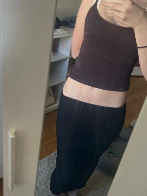 Svart ribbad långkjol från H&M - Svart långkjol från H&M i ribbat material. Kjolen har en enkel och stilren design med elastisk midja och smal passform som framhäver siluetten. Tveka inte att skriva vid frågor!