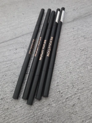 Revolution ögonbrynspenna medium brown - Säljer fem smala ögonbrynspennor från Revolution i färgen medium brown. Pennorna har svart hylsa med guldtext och är enkla att använda för att forma och fylla i brynen. Perfekt för dig som vill ha naturligt definierade ögonbryn. De är som nya.