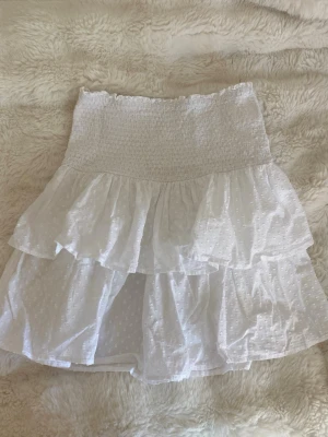 Vit volangkjol - Söt vit kjol med volanger, perfekt till sommaren. Finns ingen lapp så vet inte vart den är ifrån men skulle säga storlek s/m.