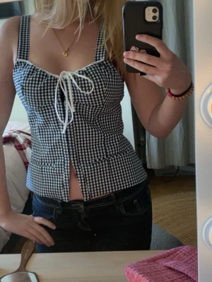 Rutig korsettopp med snörning - Tröjan är i storlek Large, men jag själv skulle säga att den passar mig som ligger mellan S och M i vissa toppar. Supersnygg rutig korsettopp i mörkblå och vitt med breda axelband och snörning framtill. 
