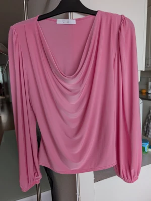 Rosa draperad blus Sisters Point - Fantastiskt fin och skön rosa blus från Sisters Point med draperad front och långa ärmar. Tillverkad i ett tunt, mjukt material som ger ett snyggt fall. Står stlk L men skulle definitivt säga M för den är för tight över magen för mig som är stlk L tyvärr 😥Absolut nyskick. Skickar snabbt.