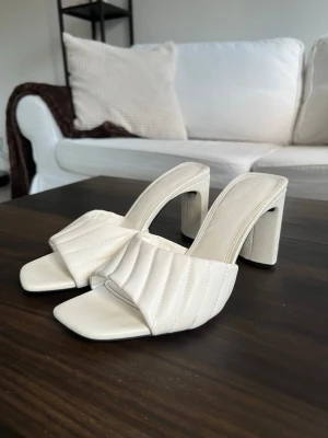 Vita quiltade slip-in pumps - Jättefina klackar/mules från Bershka i storlek 37.  Köpta via Sellpy men har själv aldrig använt dem, så de är i mycket fint skick. Säljer dem vidare då de tyvärr inte kommer till användning.  Klackhöjd: ca 9 cm