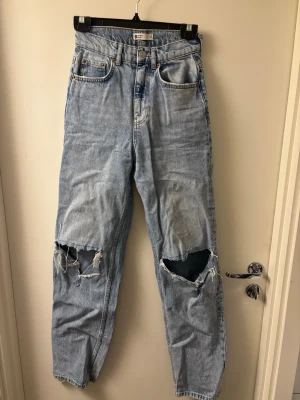 Ljusblå ripped jeans från Gina tricot - Säljer ett par ljusblå Gina tricot jeans med hög midja och raka ben. Jeansen har stora slitningar och hål över båda knäna för en riktigt trendig och avslappnad look. 
