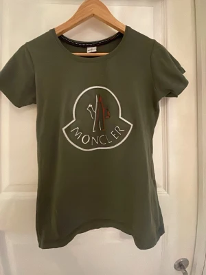Moncler t shirt - Säljer denna sjukt snygga moncler t shirten i storlek M men skulle verkligen säga att det är xs-s eftersom den sitter är tajt på mig som normalt har s den är jättefin och ger en fin figur och ser helt oanvänd ut förutom 2 fläckar på ryggen som är blekta tröjan är i bomull förutom detaljerna på framsidan  