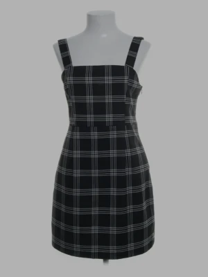 Rutig svart tajt klänning från H&M Divided - Snygg svart klänning med vita rutor från H&M Divided. Kort modell med breda axelband och figurnära passform. Perfekt för dig som gillar en stilren och trendig look. Tillverkad i mjukt material som känns bekvämt hela dagen.