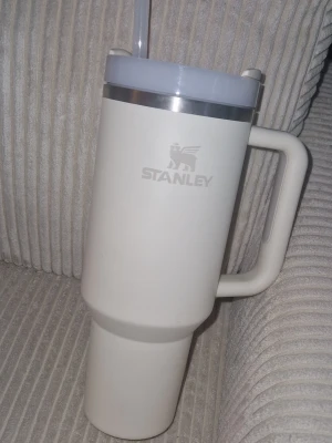 Stanley vit termosmugg med sugrör - Stanley Quencher H2.0 Flowstate™ Tumbler håller din dryck kall i 11 timmar eller upp till två dagar om du tillsätter is. Perfekt att ha med sig oavsett om du är på jobbet, tränar eller är ute och reser. Muggen har ett ergonomiskt handtag med en yta som ger bättre grepp och en smal bas som gör att den passar i de flesta bilars mugghållare. Det smarta FlowState™-locket är roterande med tre lägen: stängt läge för transport, en bredare dricköppning och ett sugrörs-läge. Sparsamt använd!