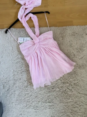 Ljusrosa halternecktopp - Supersöt slutsåld ljusrosa halterneck topp från Gina tricot.Säljer pga att den är för liten.Toppen har dragkedja på kanten och är aldrig använd.Köp gärna💕