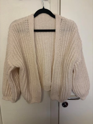 Beige stickad kofta med ballongärm - Mysig beige stickad kofta med öppen front. Använd 1 gång