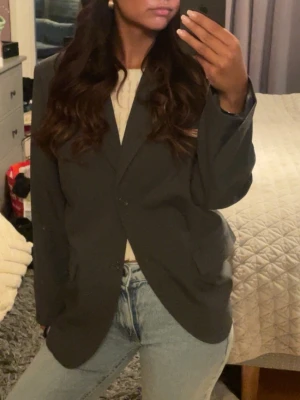 Oversized svart kavaj - Stilren oversized svart kavaj med klassisk krage och två framfickor. Kavajen har en rak passform och stängs med två knappar framtill. Perfekt att slänga över en t-shirt och jeans för en cool look.