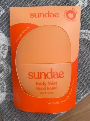 Sundae Body Mist Mood Board 90ml - Fruktig body mist från Sundae i en snygg orange flaska. Doften har inslag av svartvinbär, passionsfrukt, bergamott, citron, fresia, magnolia, bär, pion, ros, ekmossa, amber och cederträ. Innehåller kamomill och aloe vera. Passar både hår och kropp.